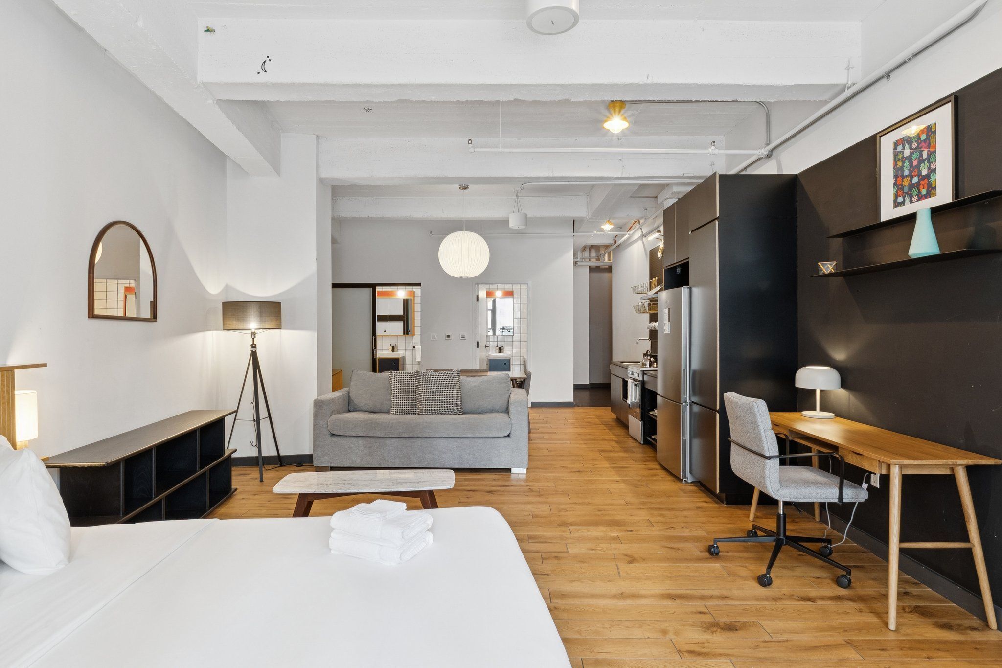 Una habitación de hotel moderna con una cama grande, un escritorio, un sofá y una kitchenette.