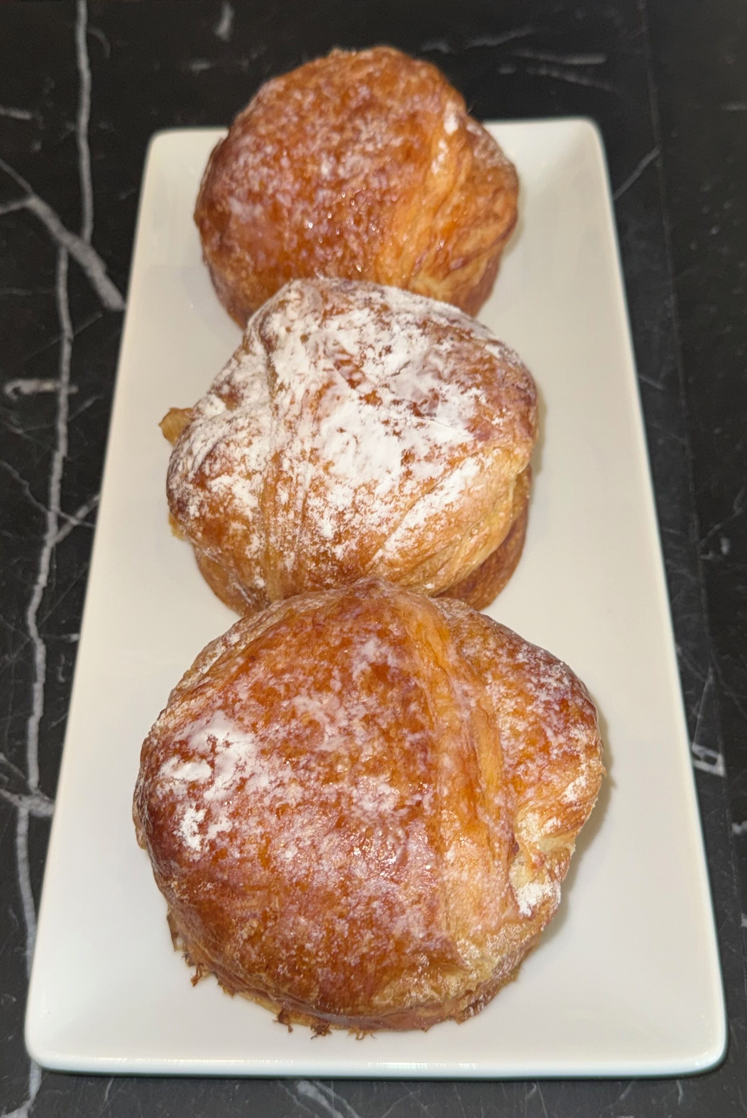 Three pastries on a white rectangular plate.