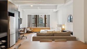Una habitación de hotel moderna con suelo de madera, un sofá, un escritorio y una cama.