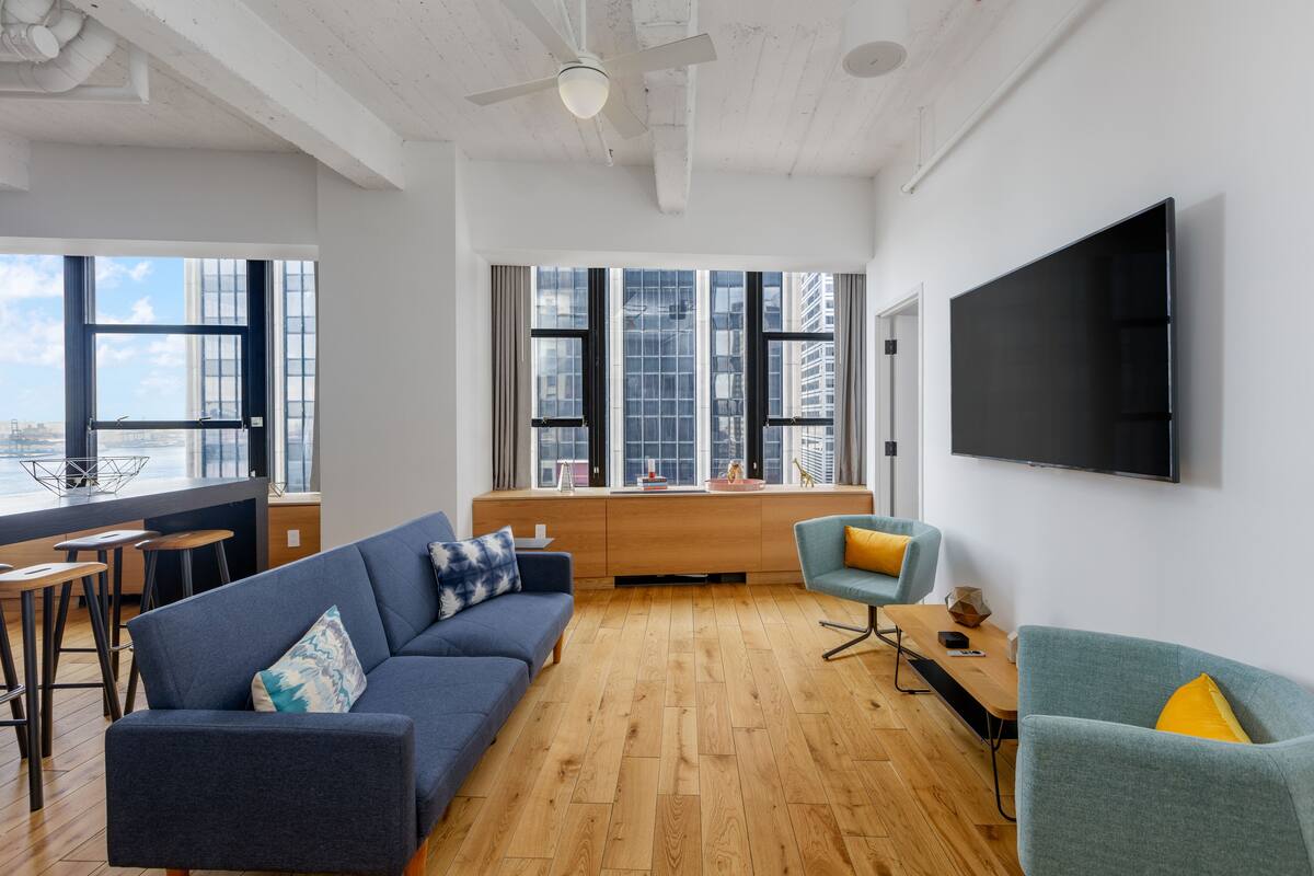 A modern living room with a blue sofa, teal armchair, and wooden flooring.