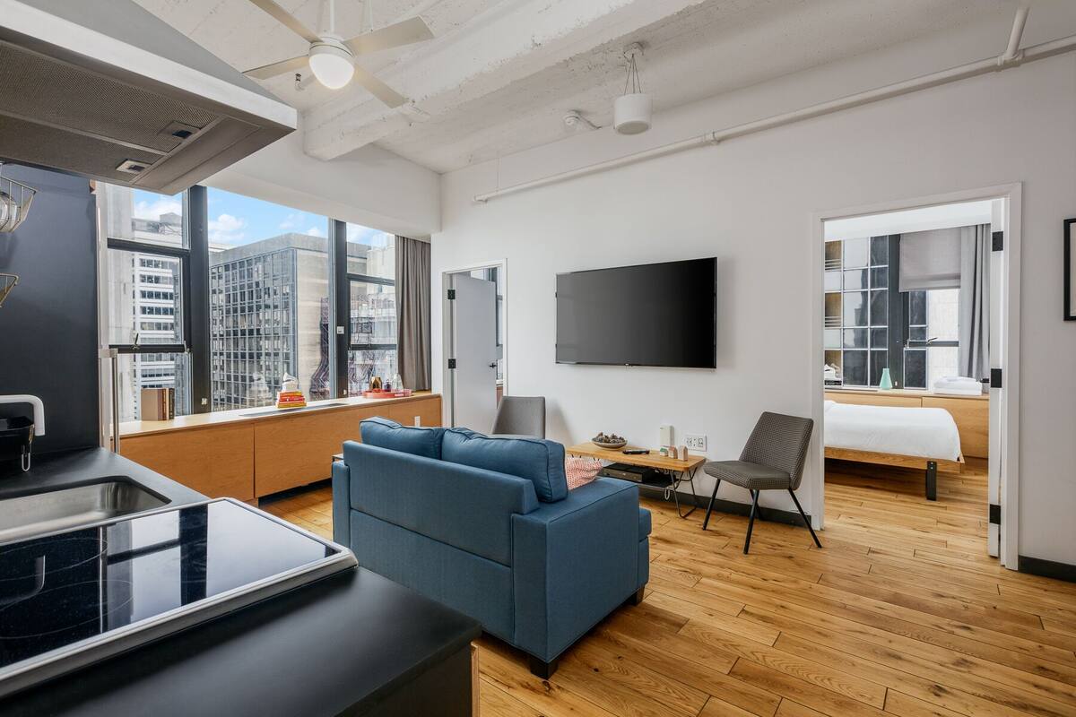 A modern living room with a blue sofa, a TV, and a city view.