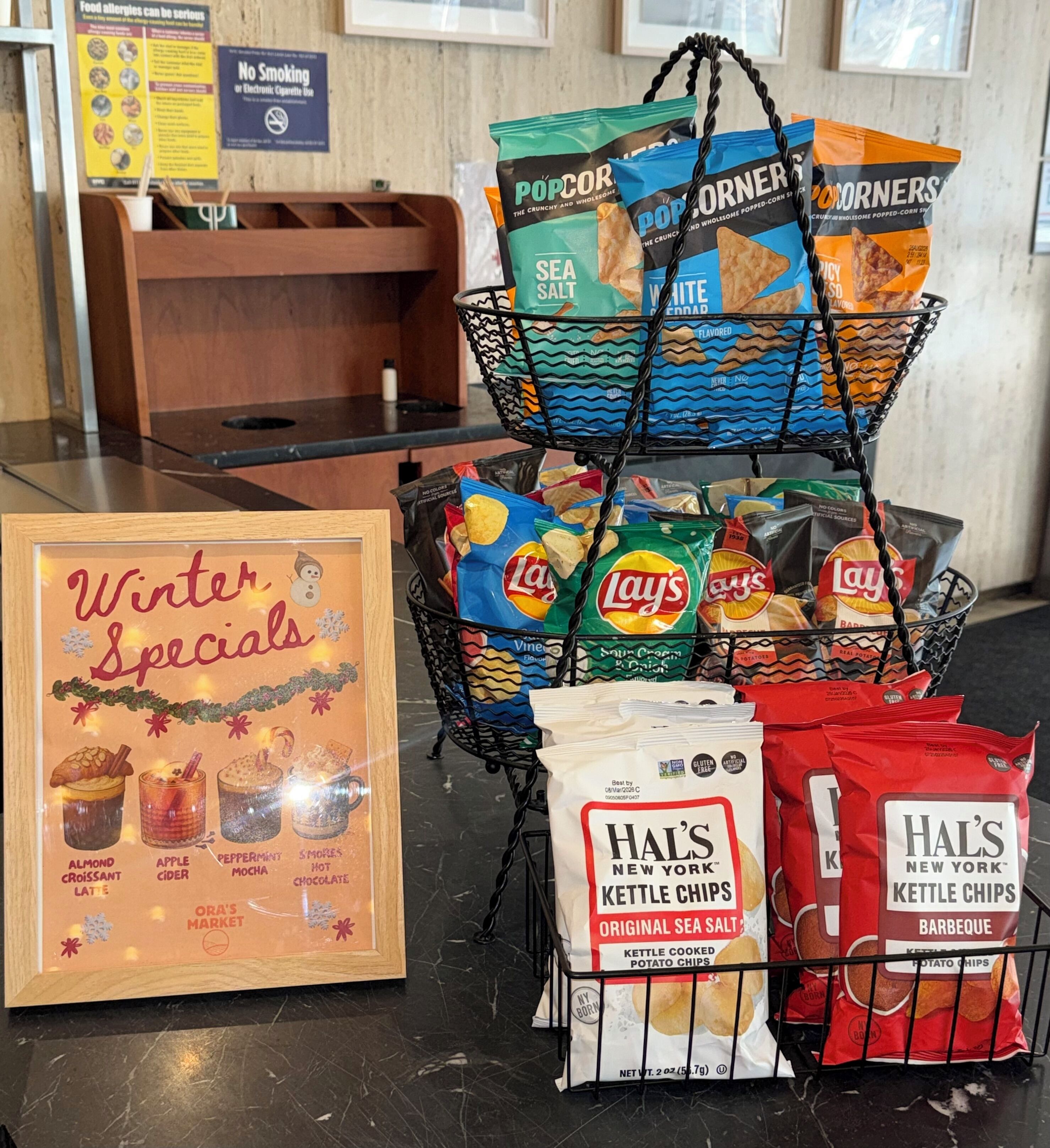 A snack display with bags of popcorn, Lay's chips, and Hal's kettle chips.