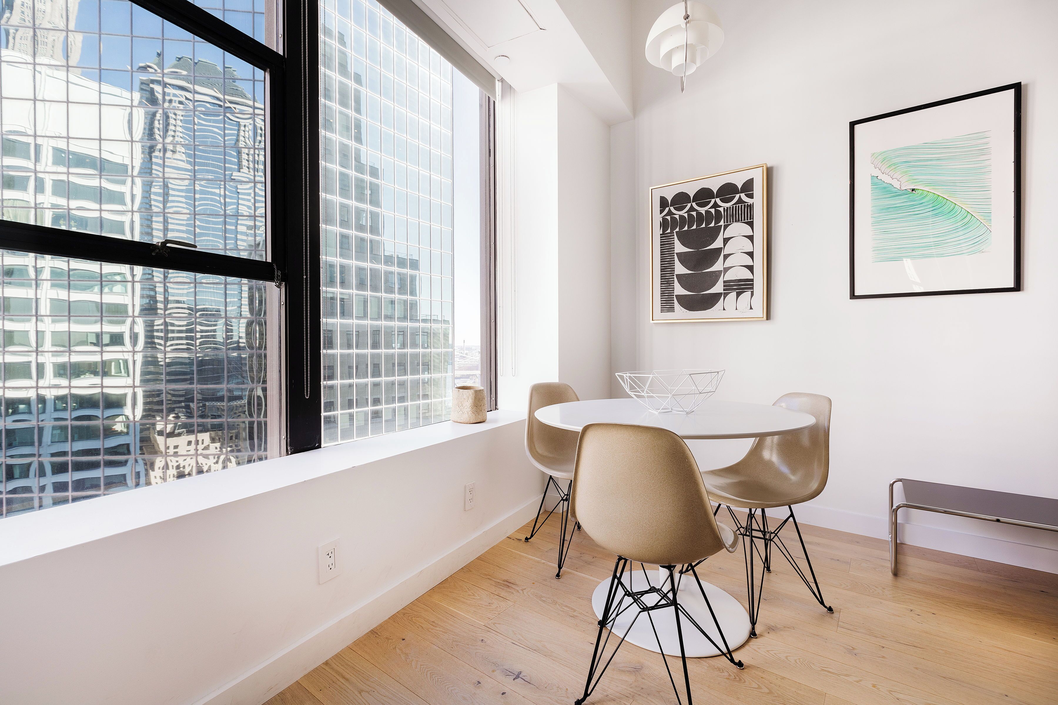 A modern dining area with a large window, a round table, and two chairs.