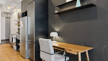 A modern kitchen with a built-in refrigerator, a wooden dining table, and a grey chair.