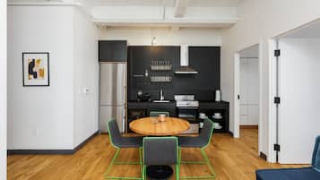 A modern kitchen with a round wooden table, two chairs, and a built-in oven.