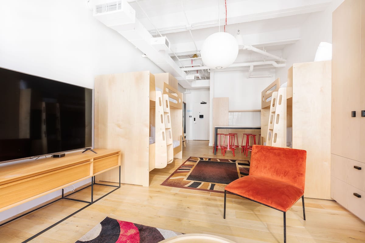 A modern living room with a flat-screen TV, wooden furniture, and a red chair.