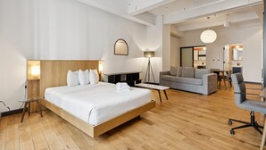 Una habitación de hotel moderna con una cama grande, un sofá, un escritorio y una silla.