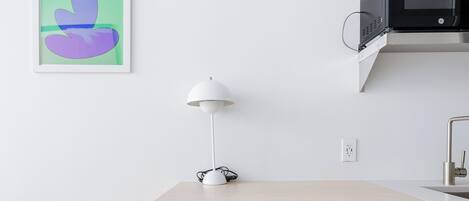 Una cocina moderna con encimera de madera, una lámpara blanca y una silla azul.