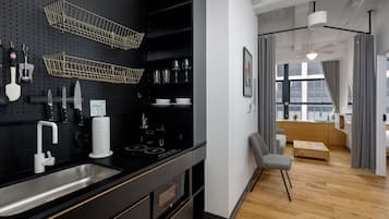 A modern kitchen with a black pegboard wall, stainless steel appliances, and a wooden dining area.