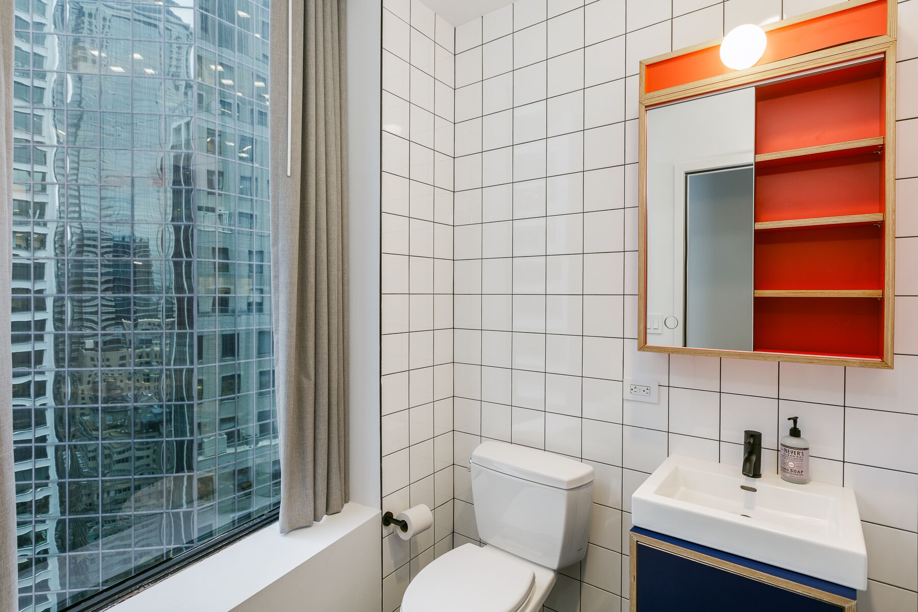 Een moderne badkamer met toilet, wastafel en spiegel.