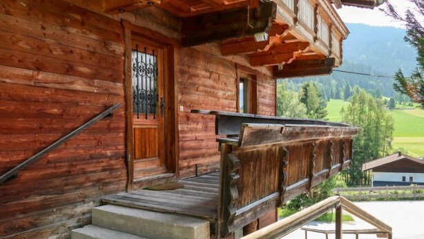 A wooden cabin with a wooden door, a set of concrete steps, and a wooden railing. - Jaggler by Interhome (Wildschönau)