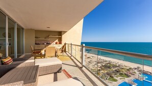 A balcony with a view of the beach and ocean.