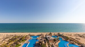 A resort with multiple swimming pools, a beach, and a clear view of the ocean.