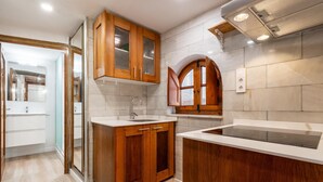 A modern kitchen with wooden cabinets, a sink, and a built-in stove. - Apartment in TGN historic center only 450m beach (Tarragona)