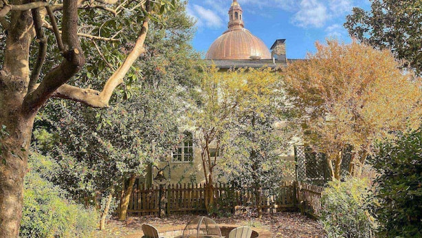 Um jardim com cerca de madeira, um banco e um gazebo.