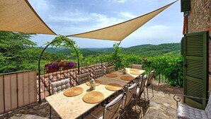 An outdoor patio with a table set for four, surrounded by cushioned chairs, under a large canopy. - Villa Collina - Holiday House Rental with private swimming pool in the small  village of Montegi... (Montegiove)
