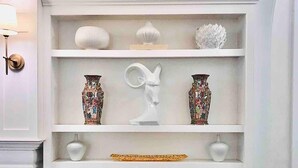 Un interior blanco con una estantería mostrando varios objetos decorativos.