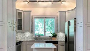 Una cocina moderna con armarios blancos, una isla central, horno empotrado y refrigerador.