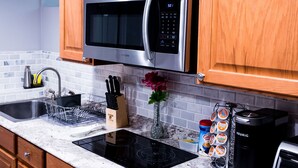 Una cocina con gabinetes de madera, un microondas de acero inoxidable, una cafetera y un tostador.