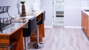 Una cocina moderna con armarios blancos, encimera de mármol y vista al área de comedor.