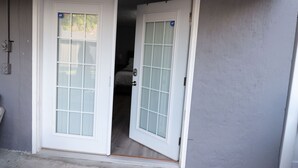 Conjunto de puertas blancas con paneles de vidrio esmerilado, que dan paso a una habitación con cama y una manija visible.