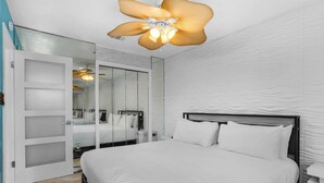 A modern bedroom with a large bed, a ceiling fan, and a mirrored closet. - Ground Floor Condo | 2-Min Walk to Beach | Pools | Tennis | Shuffleboard | Sleeps 4 | WiFi! (Santa Rosa Beach)