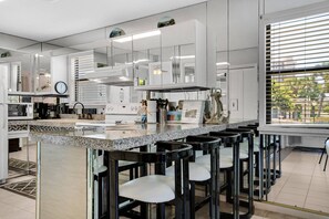 Eine moderne Küche mit Granit Arbeitsplatte, Edelstahlgeräten und einer Bar mit schwarzen Hocker.
