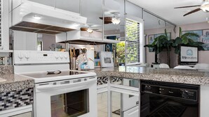 A modern kitchen with a white stove, oven, and dishwasher, a tiled backsplash, and a large window with blinds. - Ground Floor Condo | 2-Min Walk to Beach | Pools | Tennis | Shuffleboard | Sleeps 4 | WiFi! (Santa Rosa Beach)