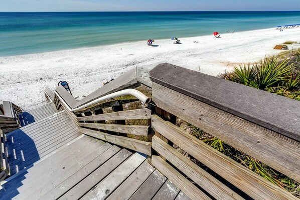 Eine Holztreppe führt zu einem Strand mit freiem Blick auf das Meer.