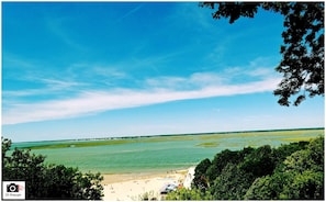 Paesaggio costiero con spiaggia, cielo sereno e costa in lontananza.
