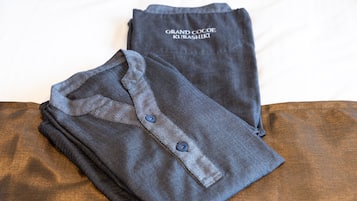 A neatly folded dark blue shirt with a collar and buttons, and a matching dark blue t-shirt with text on it, both placed on a wooden surface.