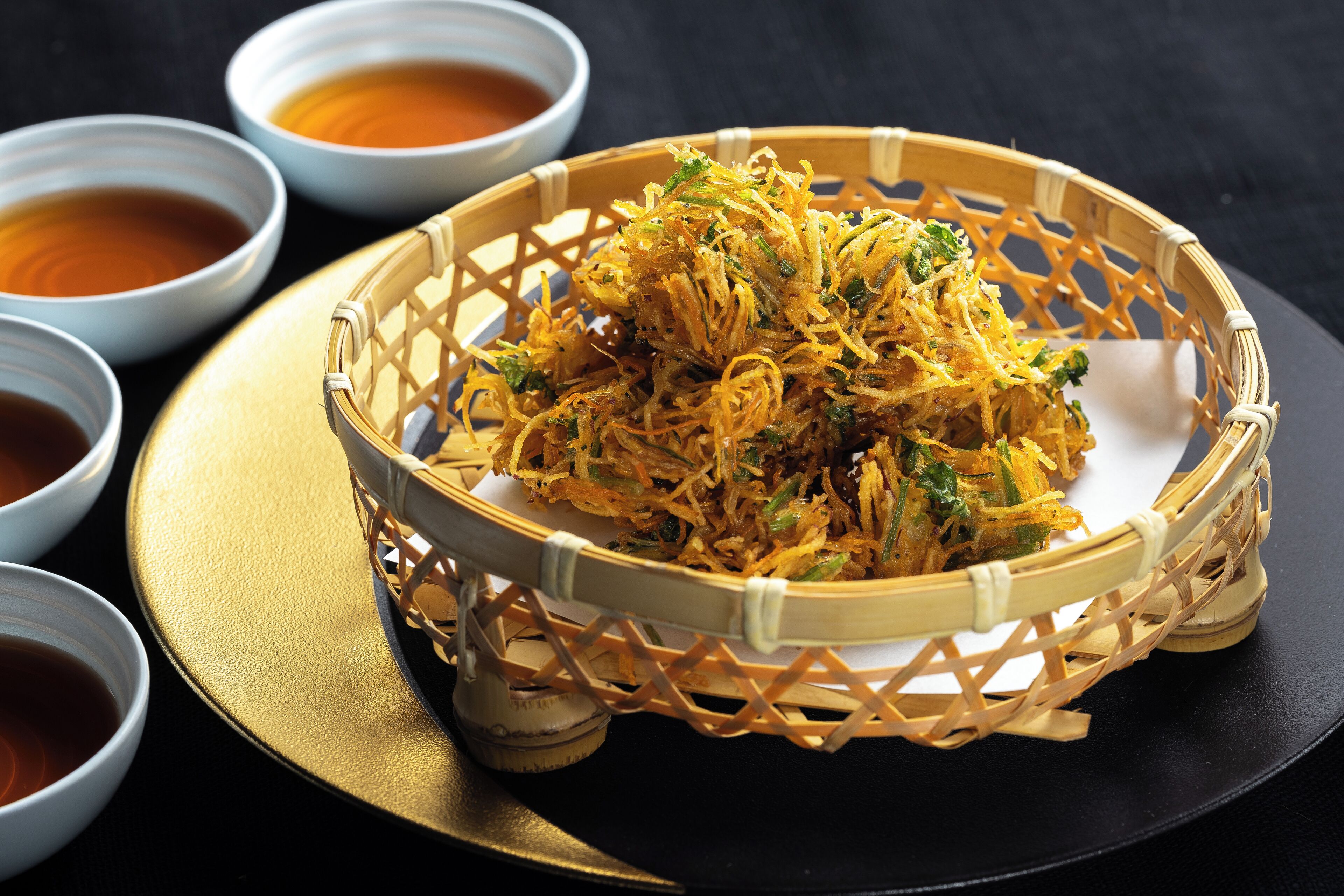 A basket of crispy fried noodles with a side of dipping sauce.
