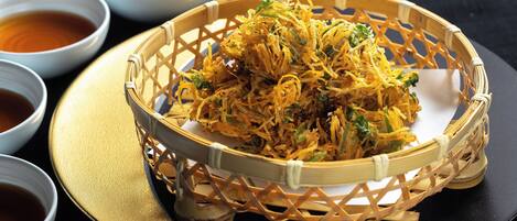 A basket of crispy fried noodles with a side of dipping sauce.