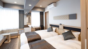 Una habitación de hotel con dos camas, un escritorio y un ventanal con cortinas.