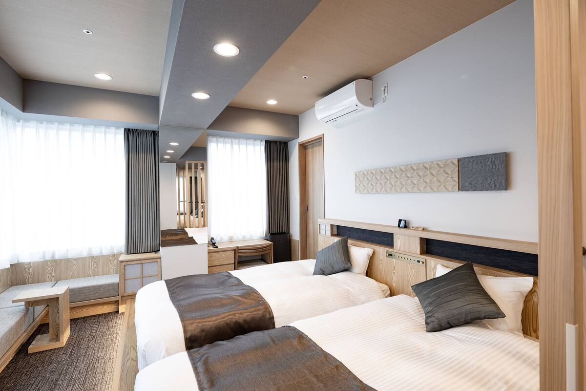 Een hotelkamer met twee bedden, een bureau en een raam met gordijnen.