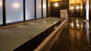 Un área de spa con una amplia piscina climatizada, paredes alicatadas y un diseño de cuadros en la pared de fondo.