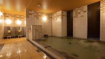 A modern indoor swimming pool with tiled walls and a wooden ceiling.
