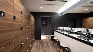A modern bathroom with wooden lockers, a large mirror, and multiple sinks.
