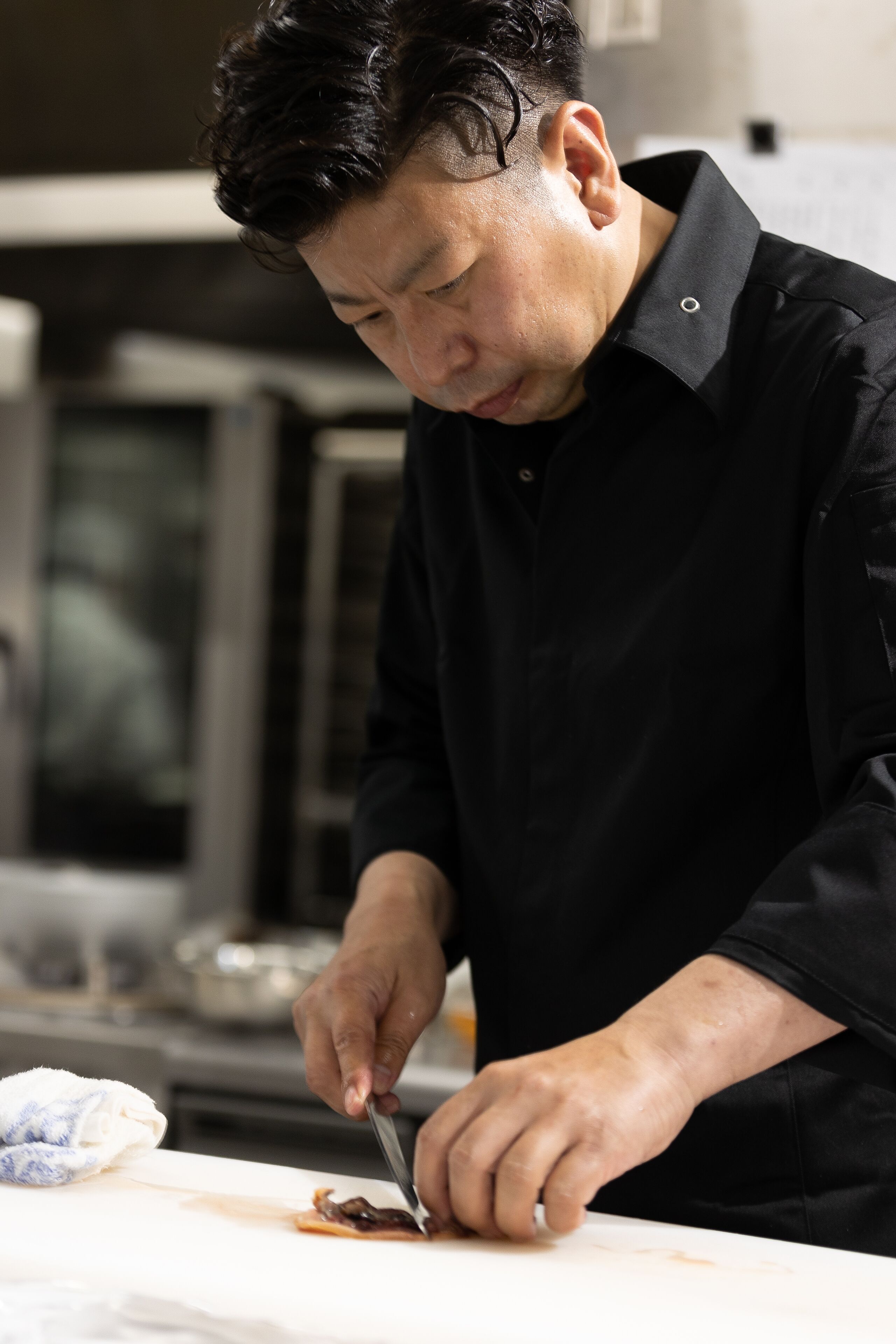 A person in a black shirt preparing food at a counter.