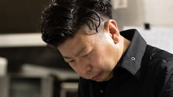 A person in a black shirt preparing food at a counter.