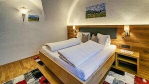 Ein Schlafzimmer mit einem hölzernen Bett, weißer Bettwäsche, einem Nachttisch, einer Wandlampe und einem Gemälde an der Wand.