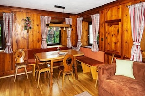 A wooden cabin interior with a wooden dining table, benches, and a sofa.