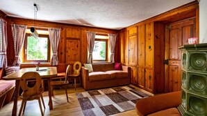 Ein gemütlicher Blockhausszimmer mit Holzwänden, einem Sofa, einem Esstisch und einem grünen Schrank.