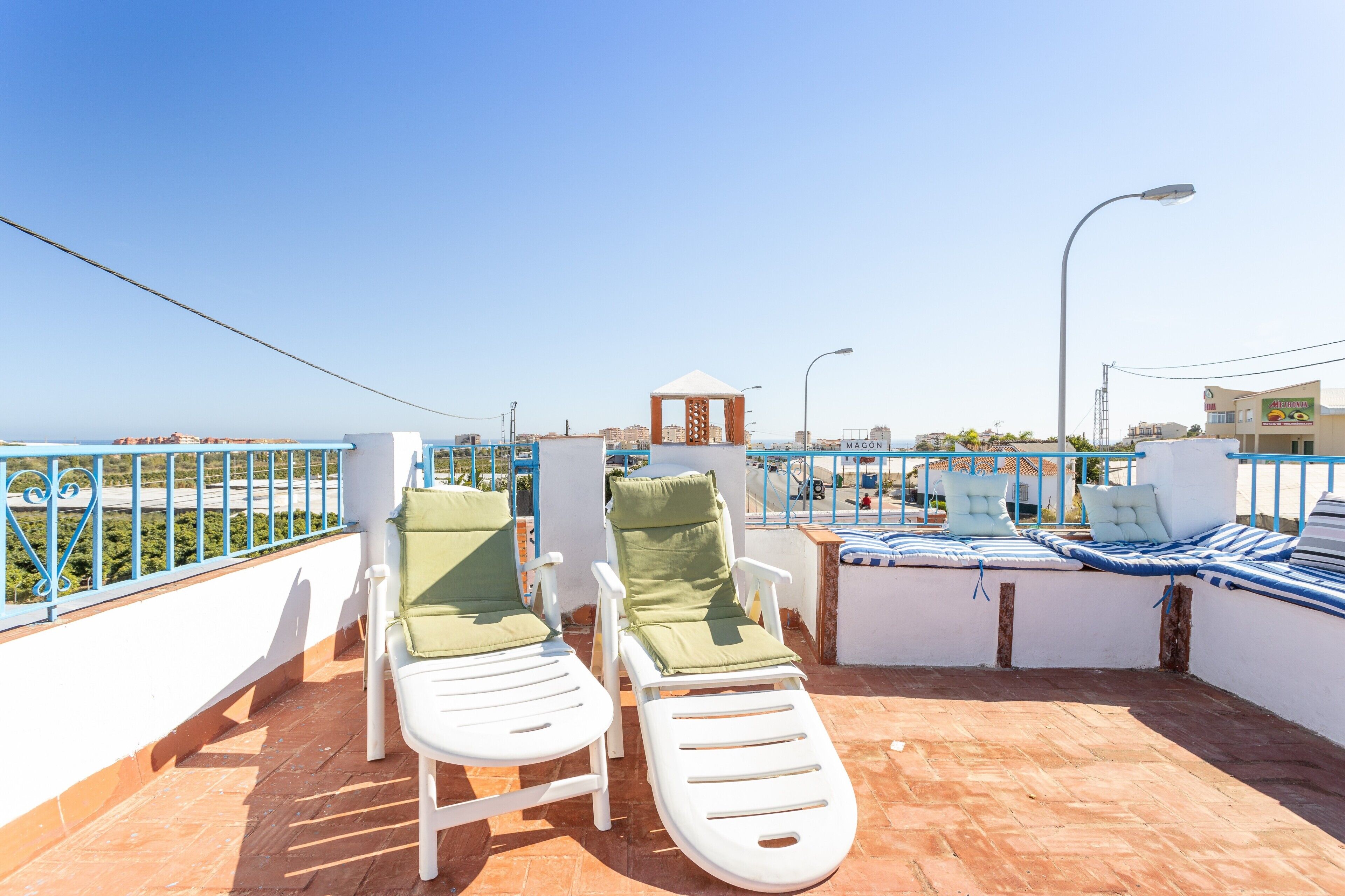 A rooftop terrace with two lounge chairs, a small gazebo, and a view of the cityscape.