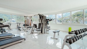 A spacious gym with various exercise equipment, large windows, and a city view. - 5 min to Los Muertos Beach in front of Cuale River located in Isla Cuale! 1BD Co (Puerto Vallarta)
