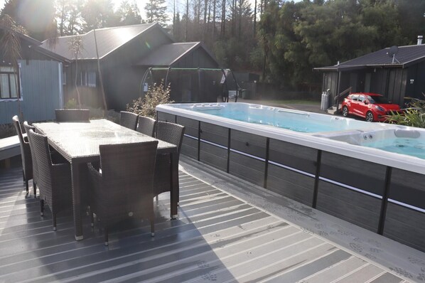 Eine Terrasse mit Whirlpool, Tisch und Stühlen.