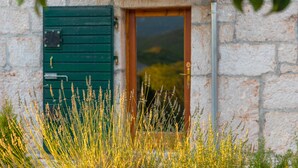 Un bâtiment rustique en pierre, doté d’une porte en bois et de volets verts.
