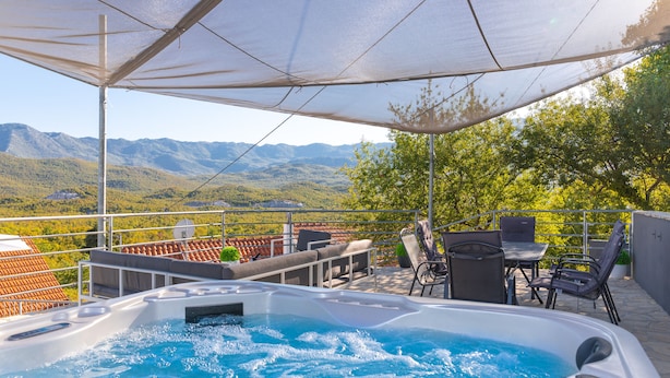 Un bain à remous avec vue sur les montagnes, un espace salon extérieur et un patio couvert.