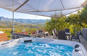 Un jacuzzi con vista a la montaña, zona de estar exterior y un patio cubierto.