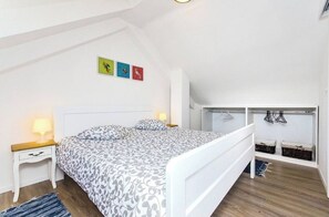 Un dormitorio con cama, mesitas de noche, una cesta colgante y una pequeña estantería.